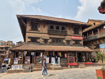 Ve�k� biela polgu�ovit� kupola budhistickej st�py Boudhanath s pozl�tenou ve�ou a o�ami M�drosti obklopen� modlitebn�mi vlajkami a n�v�tevn�kmi na n�mest� v K�thm�ndu