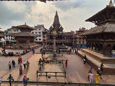 Panoramatick� poh�ad z v��ky na historick� n�mestie Kathmandu Durbar Square s kamenn�m chr�mom Krishna Mandir v �t�le Shikhara, st�pom so sochou Garudu a tradi�n�mi nep�lskymi dreven�mi pagodami obklopen�mi n�v�tevn�kmi.