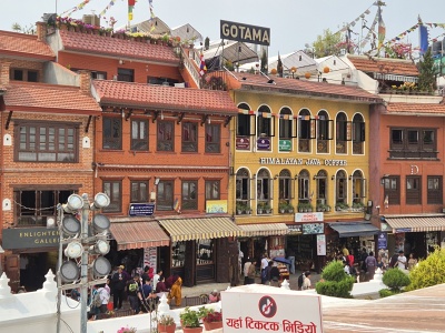 Tradi�n� viacposchodov� tehotovo-�lt� budovy s kaviar�ami ako Himalayan Java Coffee, obchody so suven�rmi a stre�n� terasy lemuj�ce kruhov� n�mestie okolo st�py Boudhanath v K�thm�ndu.