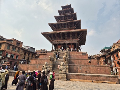 Majest�tna p�poschodov� dreven� pagoda Nyatapola na vysokom kask�dovitom tehlovom podstavci so sochami str�nych z�pasn�kov, slonov a levov na schodisku, obklopen� n�v�tevn�kmi na n�mest� Taumadhi Square v Bhaktapure.