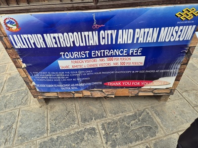 Ve�k� modr� informa�n� tabu�a mesta Lalitpur a m�zea Patan Museum s cenn�kom vstupn�ho pre zahrani�n�ch n�v�tevn�kov, umiestnen� na dl�denom n�dvor� historick�ho pal�ca