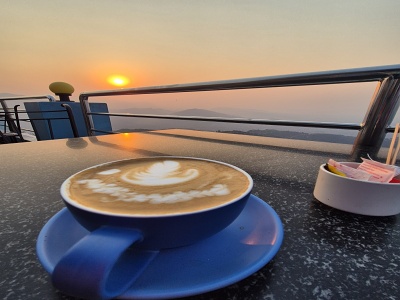 ��lka cappuccina s latte artom na stole terasy pri v�chode slnka nad hmlistou horskou krajinou v oblasti Pokhara