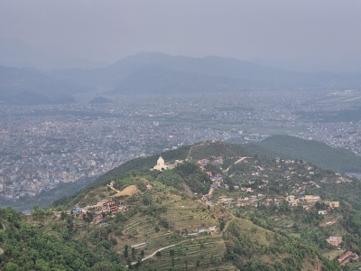 Panoramatick� poh�ad z v��ky na bielu budhistick� st�pu World Peace Pagoda na zelenom kopci nad rozsiahlym mestom Pokhara v mlie�nom opare.