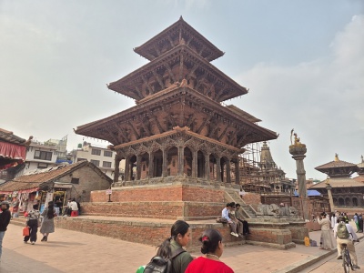 Historick� trojposchodov� dreven� pagoda Bhairavnath na vyv��enom tehlovom podstavci s okolo prech�dzaj�cimi �u�mi na n�mest� Taumadhi Square v meste Bhaktapur.