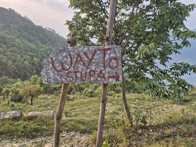 RRu�ne nama�ovan� kamenn� smerovn�k s n�pisom WAY TO STUPA pripevnen� na dreven�ch k�loch na horskom chodn�ku v Pokhare.