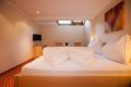 Biele periny na drevenom dvojl��ku, v pozad� stol�k s dvoma stoli�kami