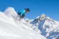 Ly�iar v modrej bunde v hlbokom snehu so zasne�en�mi horsk�mi �t�tmi v pozad�