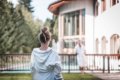 �ena v �upane na tr�vniku pri baz�ne, v pozad� mu� a budova