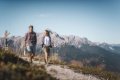 Mu� a �ena s turistick�mi palicami kr��aj� po chodn�ku pred horsk�m hrebe�om