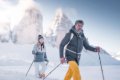 Dvojica turistov s palicami v snehu pod zasne�en�mi skaln�mi �t�tmi