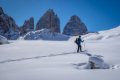 Skialpinista s batohom na snehovej pl�ni pod mohutn�mi skaln�mi ve�ami