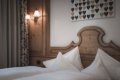 Biele vank��e pri tvarovanom drevenom �ele postele a dekor�cia so srdcami