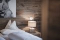 No�n� lampa s dreven�m podstavcom pri posteli a stene oblo�enej drevom