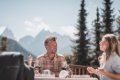 Mu� a �ena sedia pri prestretom stole na terase s horami a ihli�nanmi v pozad�
