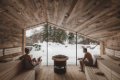Dvojica v drevenej saune s presklenou stenou a v�h�adom na sneh