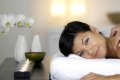 �ena pri mas�i ramena na bielom leh�tku ved�a svie�ok a orchidey