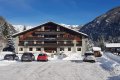 Hotel s dreven�mi balk�nmi a autami pred budovou v zasne�enom horskom �dol�