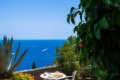 Terasa s le�adlami, stol�kom a bielymi stoli�kami nad modr�m morom