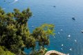 Terasa s okr�hlym stolom nad morom s lo�kami a kamenn�m schodiskom