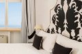 Biela poste� s tmav�mi vank��mi a v�razn�m �iernym ornamentom na stene