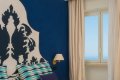 Dve l��ka pri modrej stene s ornamentom a okne s v�h�adom na more