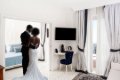 Svadobn� p�r v bielej izbe s poste�ou, telev�zorom a modrou stoli�kou