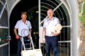 Dvaja mu�i v bielych poloko�eliach s prepravn�m voz�kom a �katu�ami pri br�ne