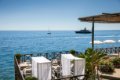 Le�adl� s bielymi z�vesmi na terase nad morom s plachetnicou a jachtou