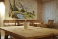 Dreven� stoly a stoli�ky v jed�lni s n�stennou ma�bou horskej krajiny