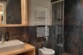 Um�vadlo na drevenej doske, bidet a sprchov� k�t v tmavo oblo�enej k�pe�ni