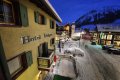 Fas�da s balk�nom nad zasne�enou ulicou, v pozad� kostol a horsk� svah