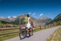 Cyklistka so zelen�m batohom na asfaltovej ceste v horskom �dol�