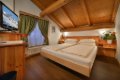 Dvojl��kov� poste� pod dreven�m tr�mov�m stropom, telev�zor a zelen� z�vesy