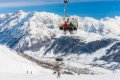 Ly�iari na seda�kovej lanovke nad svahom s kulisou zasne�en�ch h�r