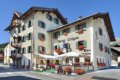 Hotel Livigno so zelen�mi okenicami, kvetmi na fas�de a terasou pri ulici