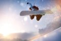Snowboardista vo v�skoku nad snehom s horami a n�zkym slnkom v pozad�