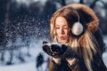 �ena v zimnej bunde s chr�ni�mi u�� f�ka sneh z �iernych rukav�c