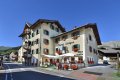 Hotel Livigno so zelen�mi okenicami, kvetmi a terasou pri ulici