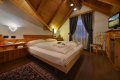 Dvojl��kov� poste� pod dreven�mi tr�mami, vzorovan� koberec a telev�zor
