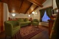 Zelen� pohovka a dve kresl� pod �ikm�m dreven�m stropom