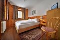 Dreven� poste� pri okne so z�vesmi a stoli�ka so vzorovan�m sedadlom